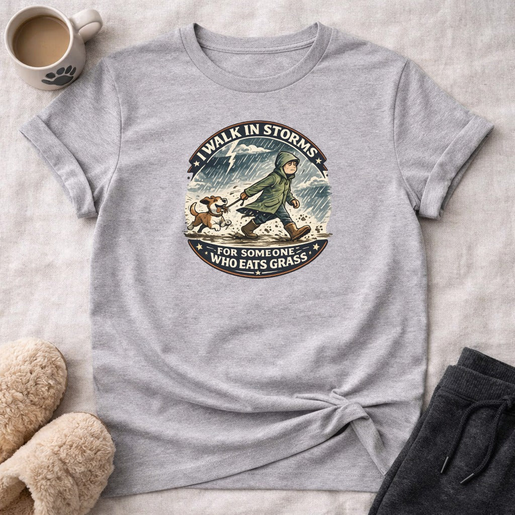 T-shirt with graphic of person walking dog in rain, text "I walk in storms for someone who eats grass."